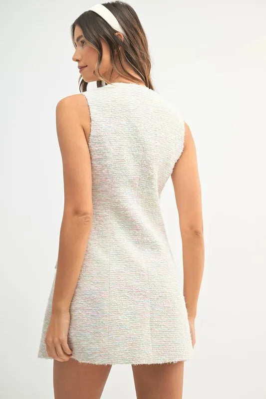 Back view of sleeveless cream mini dress showing tailored fit and straight hemline