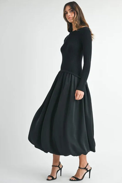 Side angle of sculpted black sweater dress with long sleeves and gathered midi skirt
