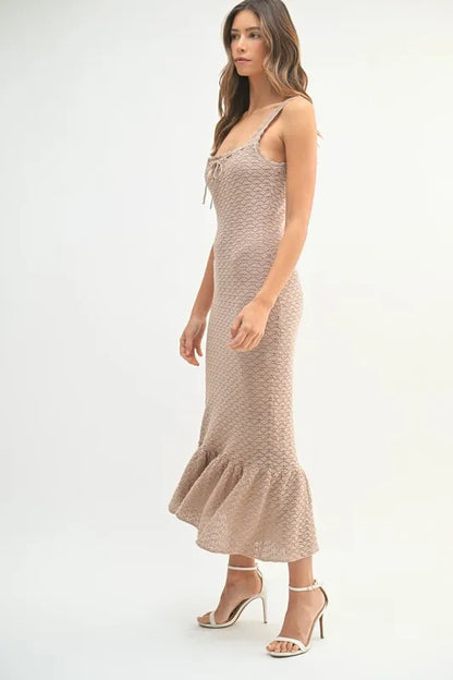 Side view of sleeveless midi dress with subtle pattern and flowy ruffle hemline

