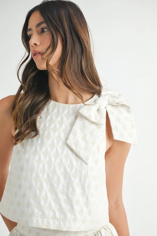 Close-up of polka dot taffeta top with large shoulder ribbon and textured fabric


