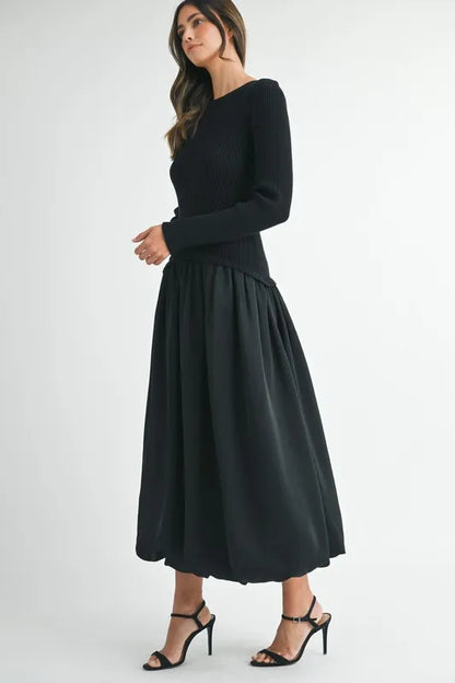 Side angle of sculpted black sweater dress with long sleeves and gathered midi skirt