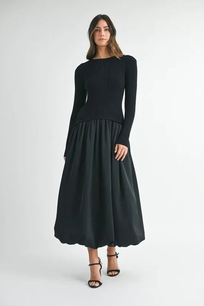 Model walking in black poplin midi dress with ribbed knit top and flared silhouette