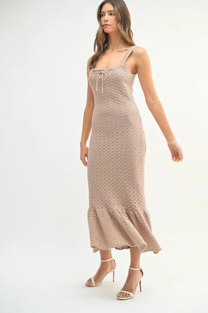 Model in ribbed neutral knit dress with flared hem and side ruching

