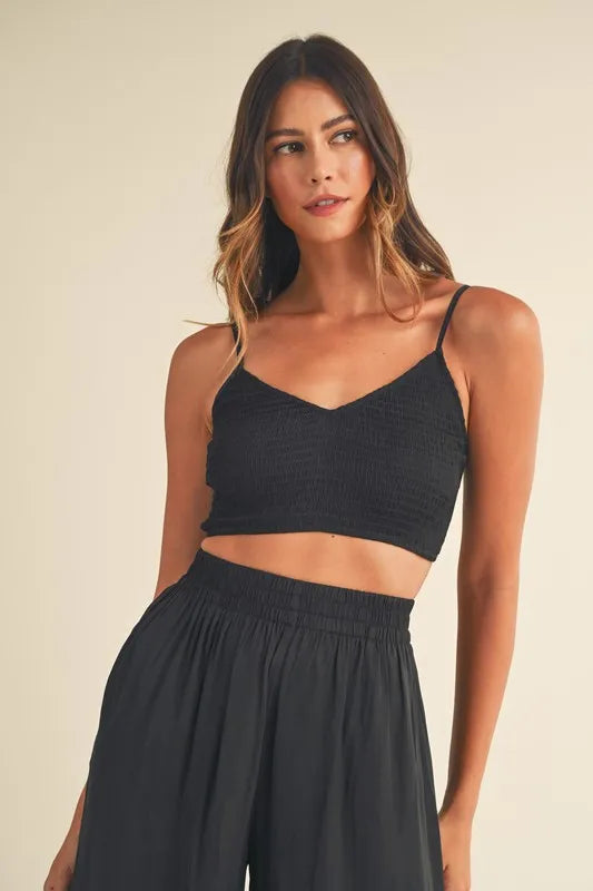 Detail of smocked bustier-style black top with stretch fit and thin straps

