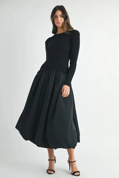 Side angle of sculpted black sweater dress with long sleeves and gathered midi skirt