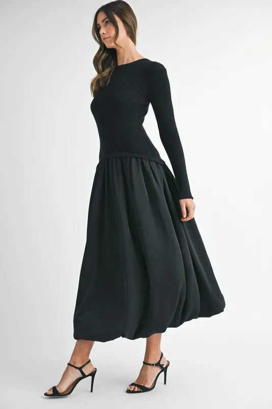 Side angle of sculpted black sweater dress with long sleeves and gathered midi skirt