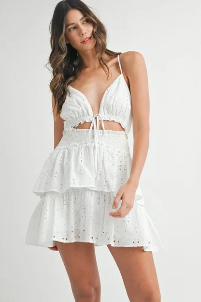 White sleeveless ruffle mini dress with front cutout, worn by model standing upright